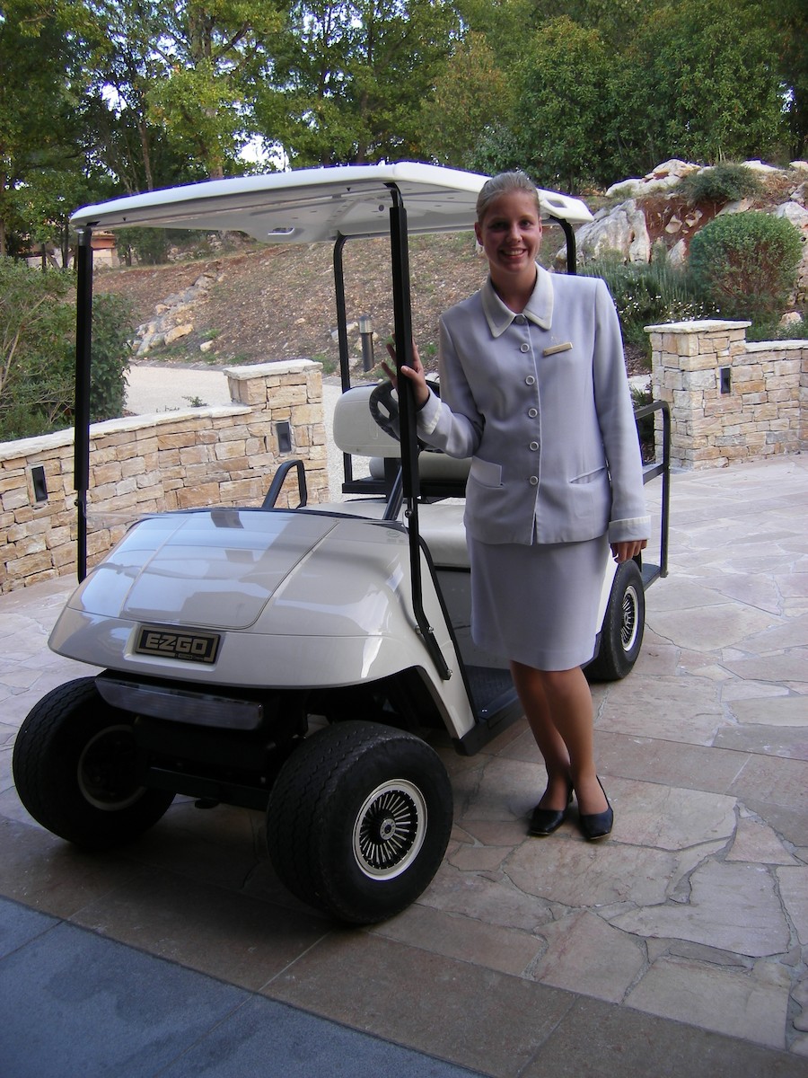 Woman in front of golf cart wearing a Four Seasons uniform