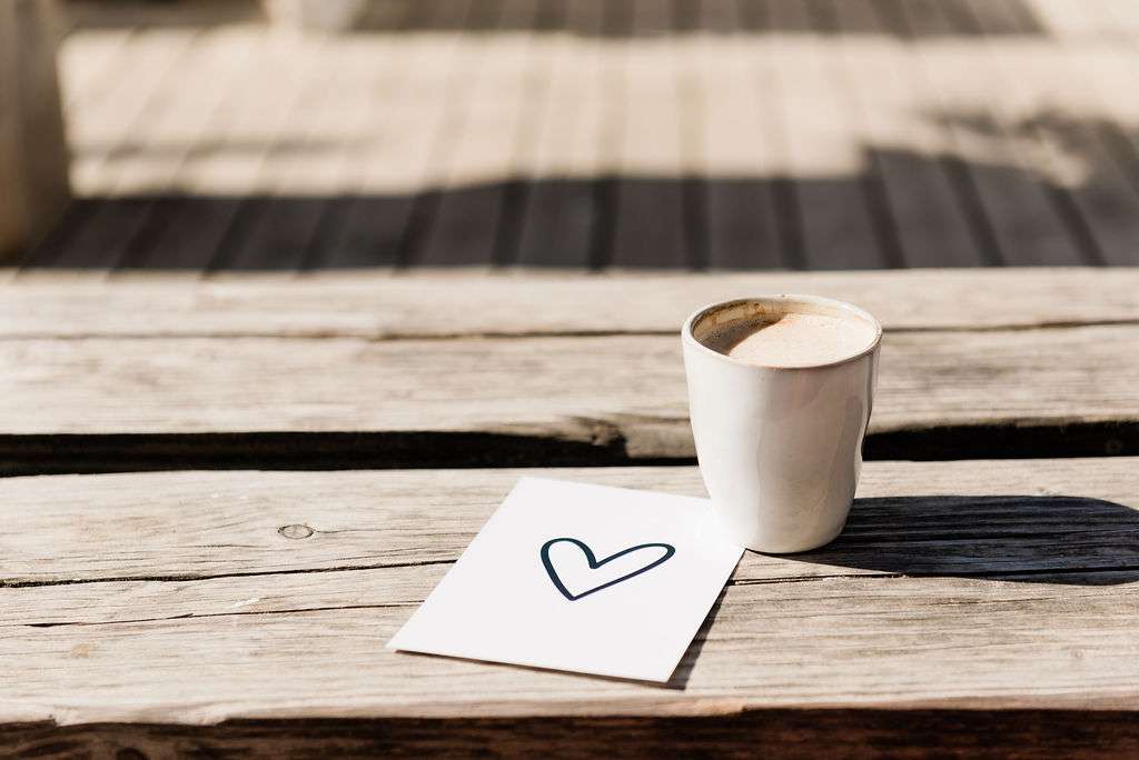 Coffee cup and heart illustration on a beach